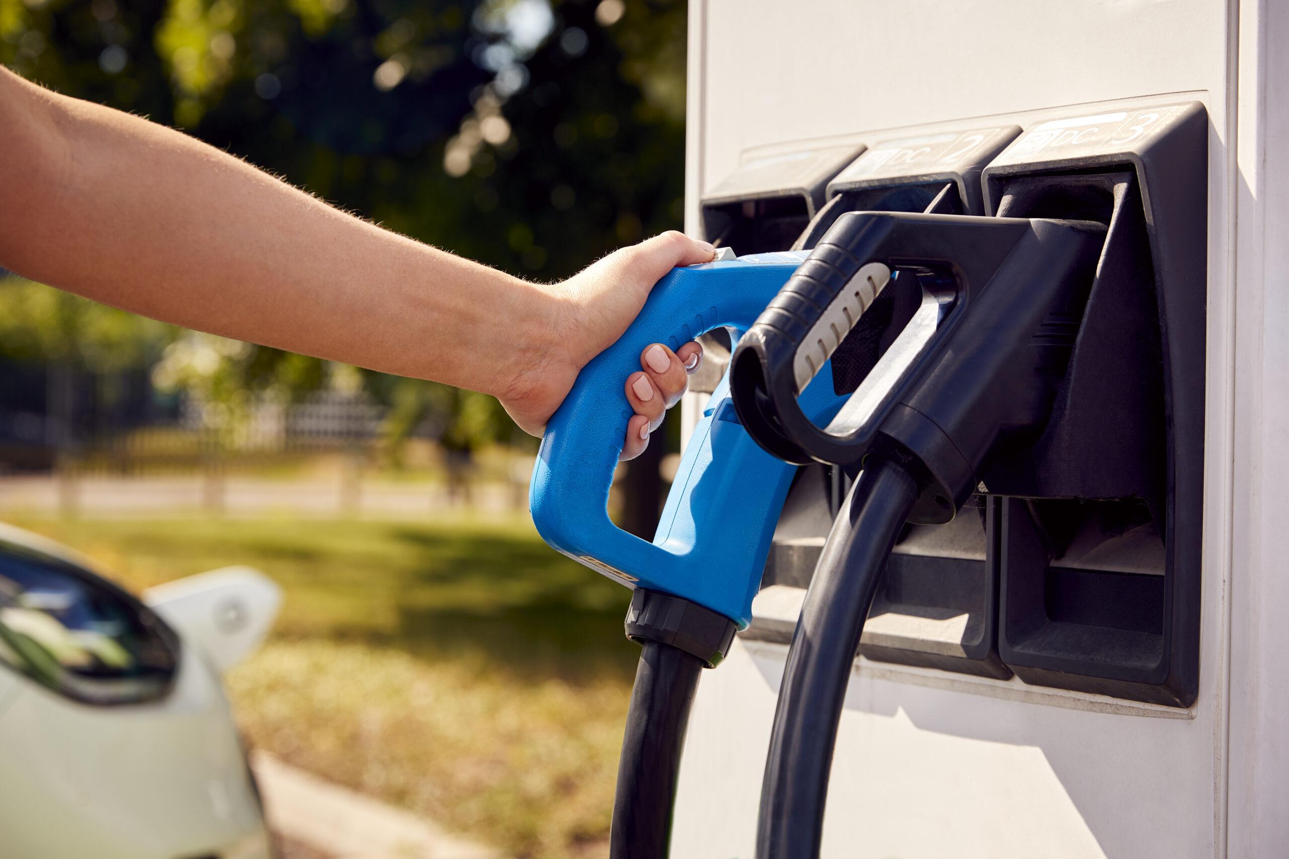 Close Up Of Hand Using Charging Station To Recharge Zero Emission Electric Car