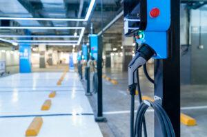 Electric car charging station for charge EV battery. Plug for vehicle with electric engine. EV charger. Clean energy. Charging point at car parking lot. Green power. Future transport technology.