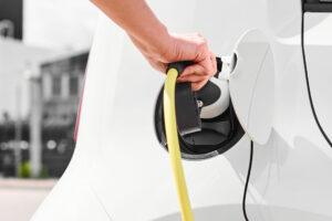 Woman unplugging a charger from an electric car socket. Eco friendly vehicle with zero emission.